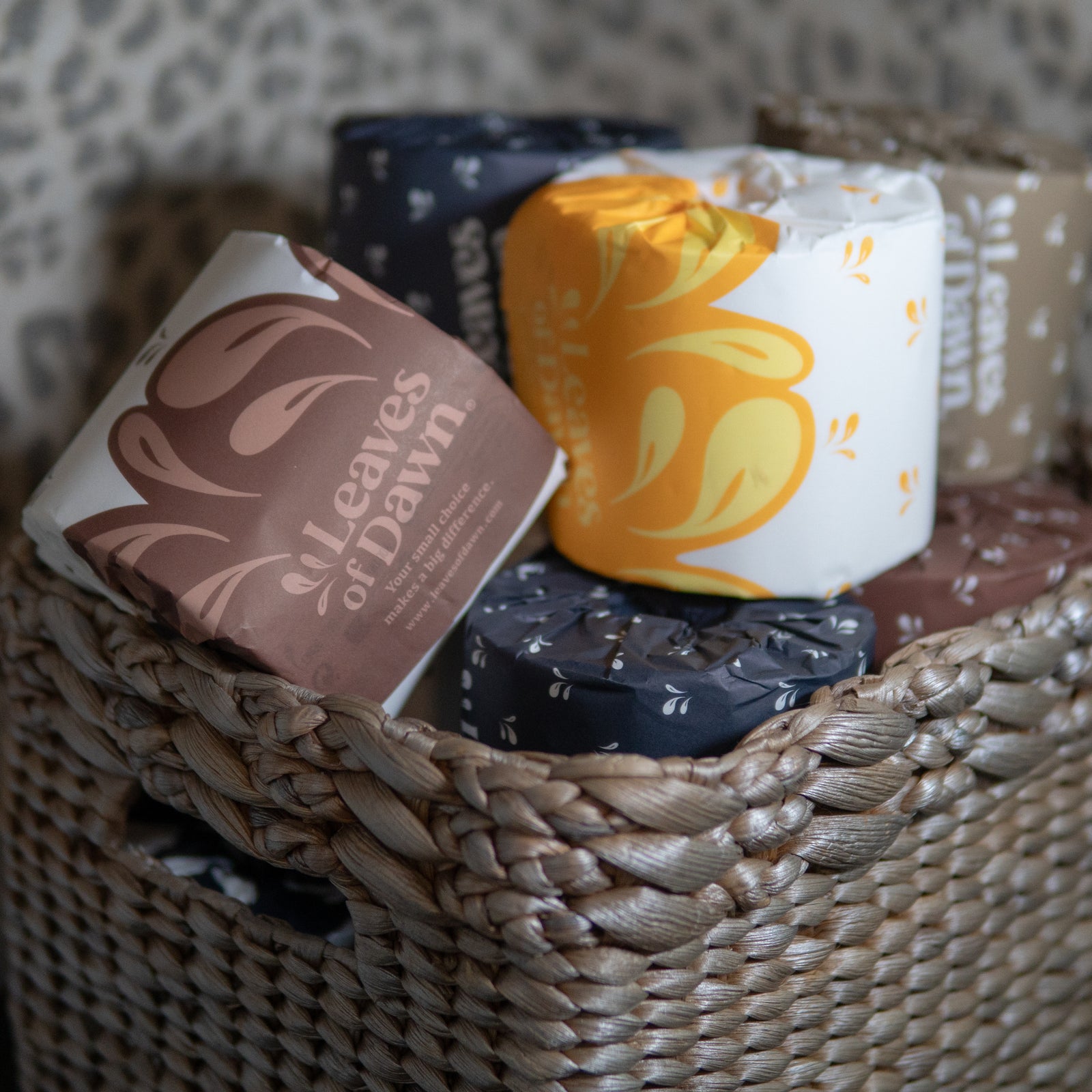 Leaves of Dawn bamboo toilet paper rolls on a bathroom basket box.